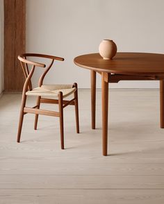 two chairs and a table with a vase sitting on top of it in an empty room