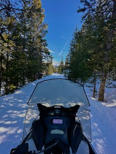 the back end of a snowmobile on a snowy road with trees in the background
