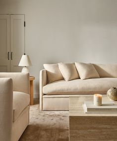 a living room filled with furniture and a lamp on top of a wooden coffee table