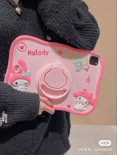 a person holding a pink camera with hello kitty on it's back and the words melody written in english
