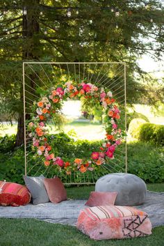 an outdoor area with flowers and pillows on the ground, including a circular mirror in the background