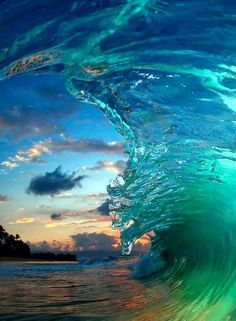 an ocean wave with the sun setting in the background