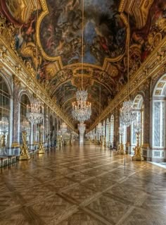 an ornate hall with chandeliers and paintings on the walls
