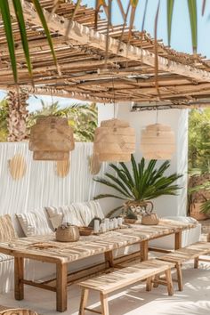 an outdoor seating area with wicker furniture and plants on the table, in front of a white wall