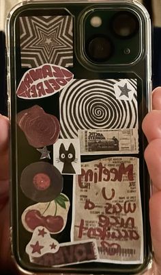 someone holding up their phone case with stickers on it