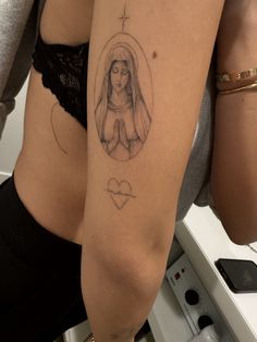 a woman's thigh with a tattoo on her left leg and the image of a virgin mary