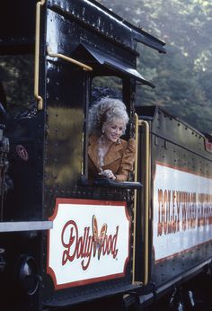 an older woman sitting in the caboose of a train with advertising on it