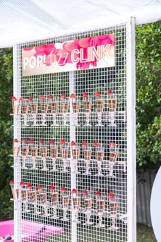 a large display of wine glasses in front of a white sign that says pop fizz clink
