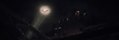 a street light shines in the night sky above a dark cityscape at night