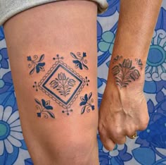 two people holding hands with tattoos on their legs