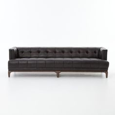 a black leather couch sitting on top of a white floor next to a wooden frame