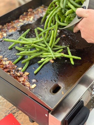 someone is cooking green beans on an outdoor grill