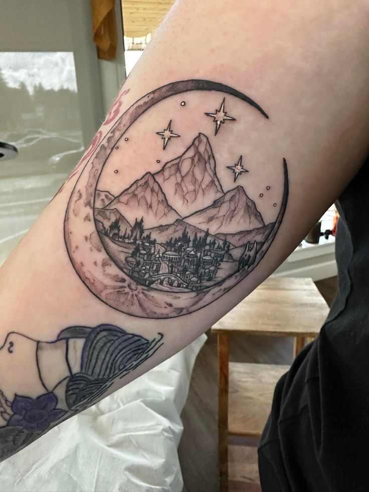 a person with a tattoo on their arm that has mountains and stars in the sky