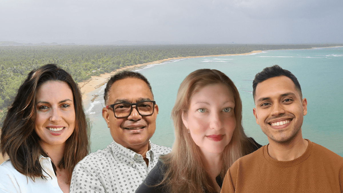 Four people smiling. A background of a beach.