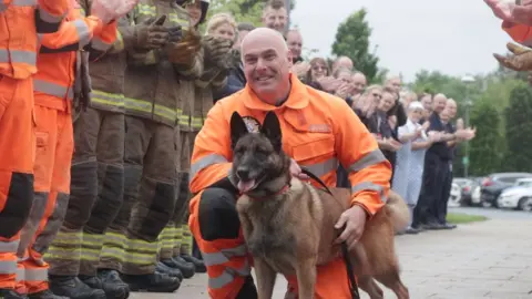 Frankie the retiring service dog with her handler Steven Carr, flanked by members of TWFRS