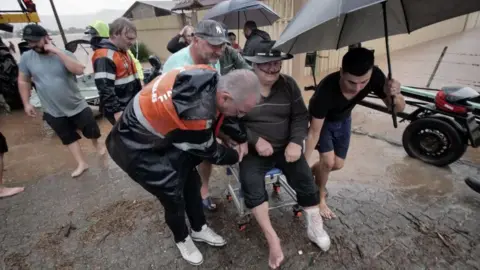A handout photo made available by the Santa Maria City Council shows a group of people helping an adult to evacuate in the rain, in Santa Maria, State of Rio Grande do Sul, Brazil, 01 May 2024.