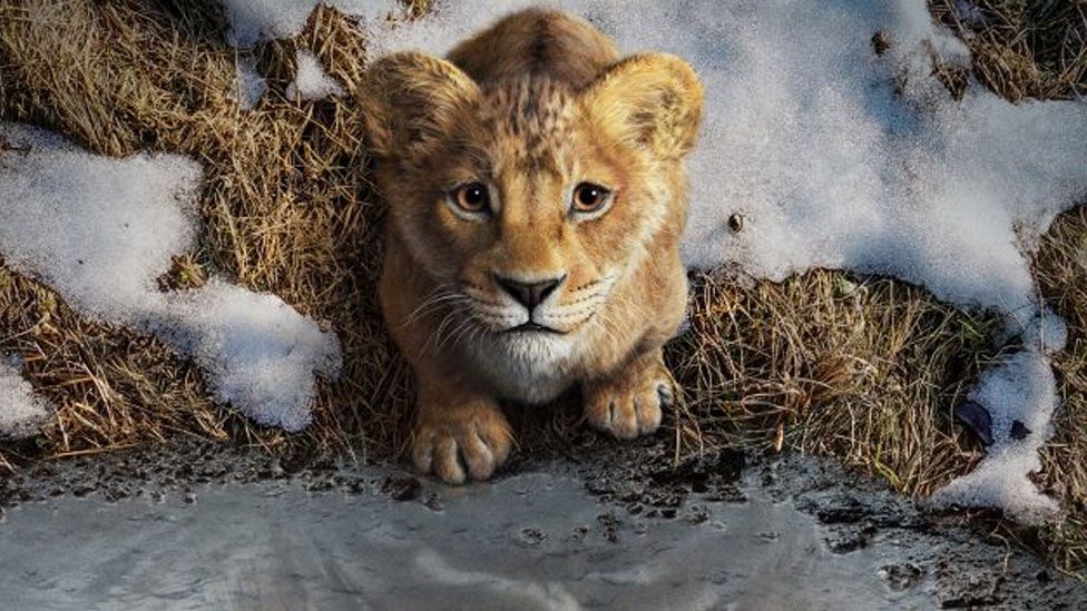 A young animated lion cub looks up, surrounded by snow on grass
