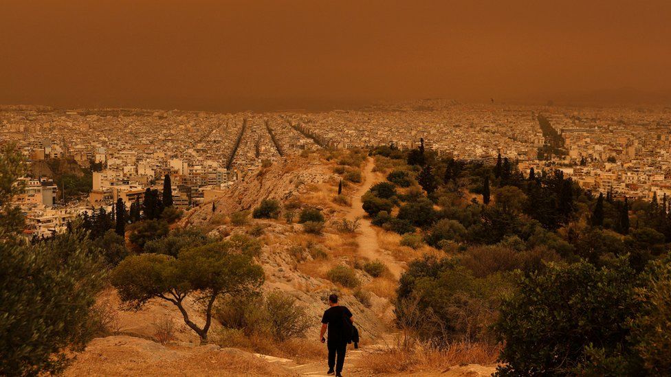man-staring-at-orange-dust-storm-in-athens.