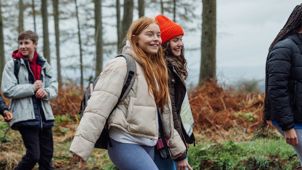 girls smiling and walking through woods on school trip