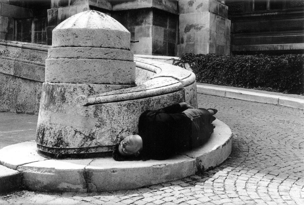 Black and white photo of a person lying on a pavement
