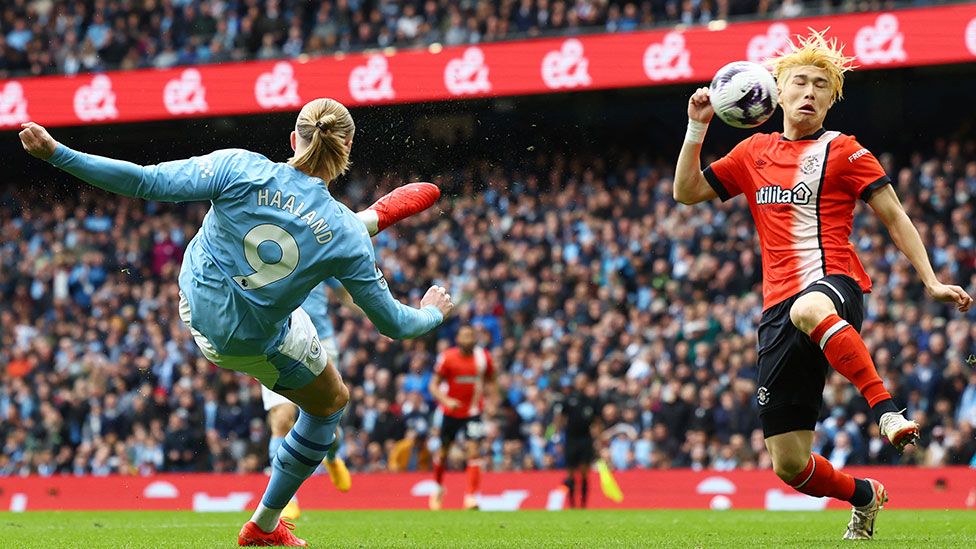 Manchester City player Erling Haaland accidentally kicks the ball towards Luton defender Daiki Hashioka's head
