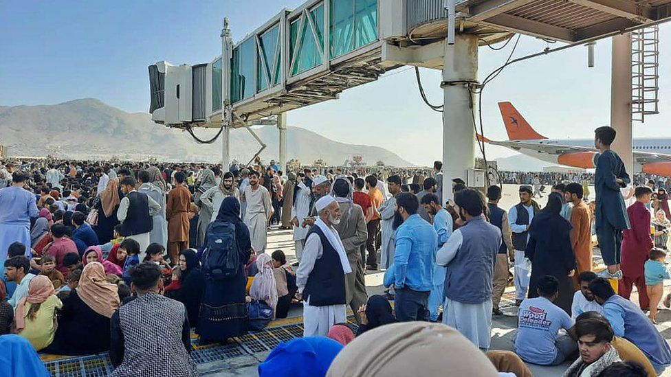 Afghans crowd at the tarmac of the Kabul airport on August 16, 2021, to flee the country as the Taliban
