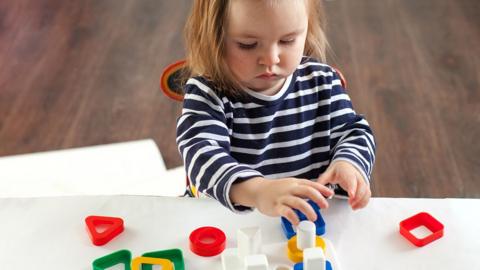 Child playing with toy on white table