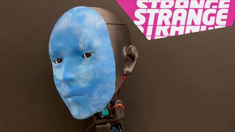 A blue robot face and the Strange News logo