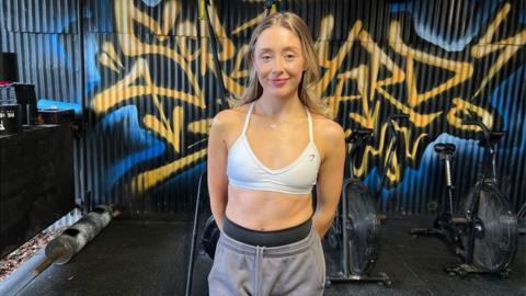 Mia Collins wearing a white sports bra and grey jogging bottoms