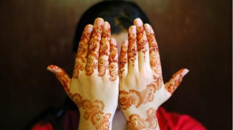 girl sholding up hands with mehndi