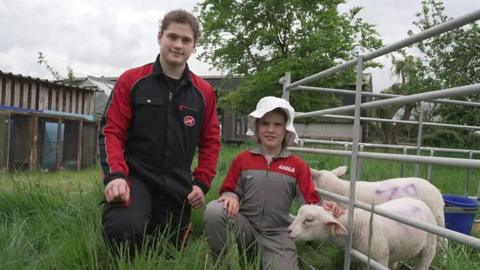 Matthew and Beatice with a lamb on a farm