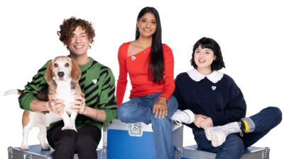 From left to right: Henry the dog is being held by Joel, Shini is in the middle and Abby is next to her. They are all looking at the camera smiling.