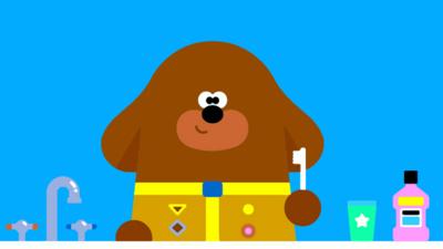 Hey Duggee holding a toothbrush.
