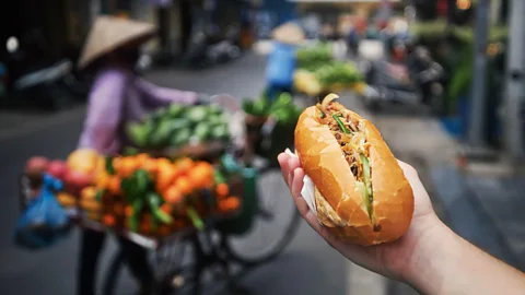 hand holding banh mi on the street