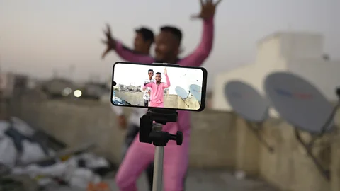 A mobile phone on a stand films two Indian men as they make a video (Credit: Getty Images)