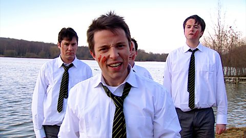 Four boys in shirts and ties outdoors with blood smears on their faces