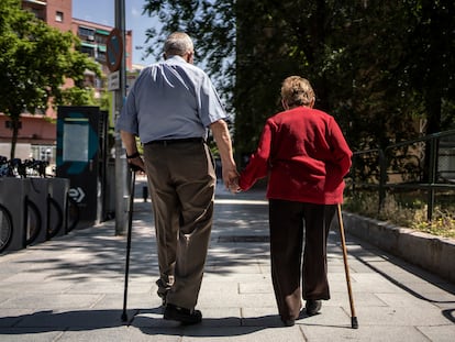 Dos ancianos caminan de la mano por una calle de Madrid.