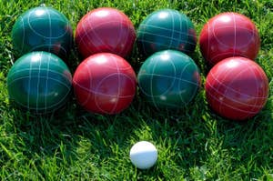 A set of bocce balls on grass with one small white ball, ideal for outdoor games