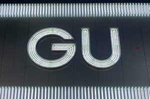 壁に取り付けられた「GU」という文字の照明サイン。