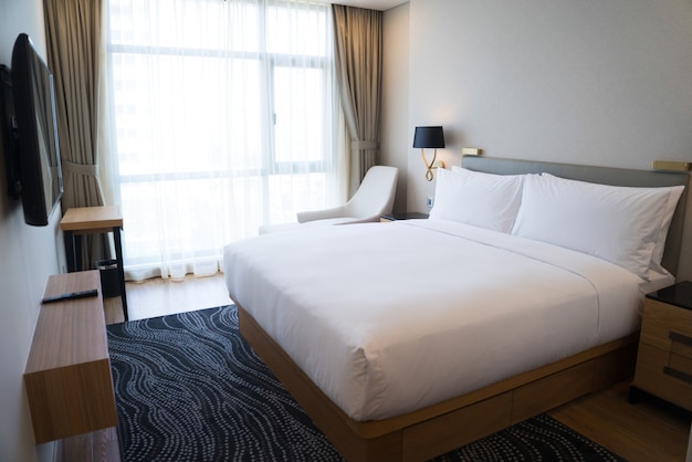 Photo gratuite petite chambre d'hôtel avec des murs blancs et une fenêtre panoramique.