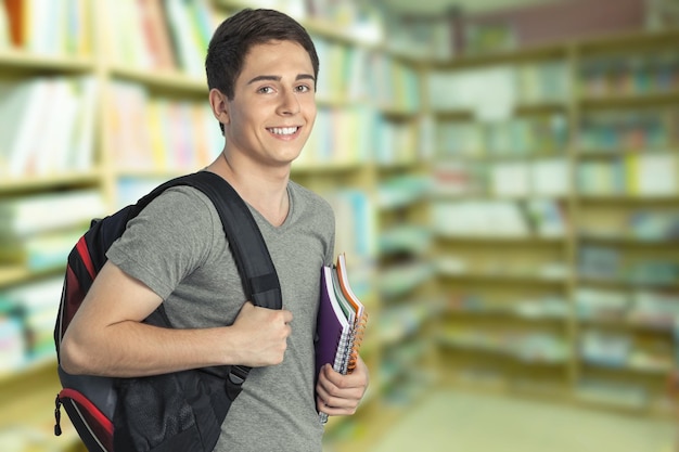 Photo un beau garçon souriant avec des livres en arrière-plan.