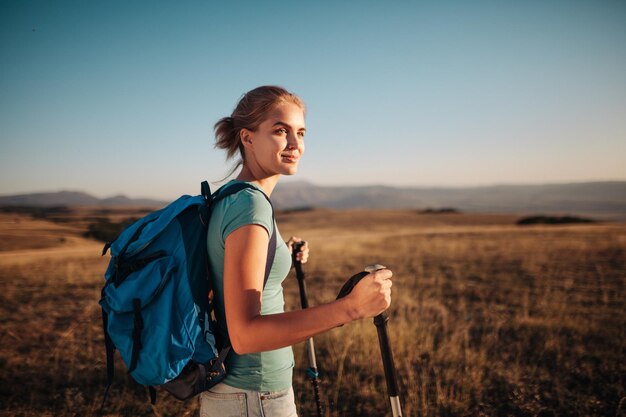Photo une jeune femme en randonnée dans les montagnes debout sur une crête rocheuse avec un sac à dos