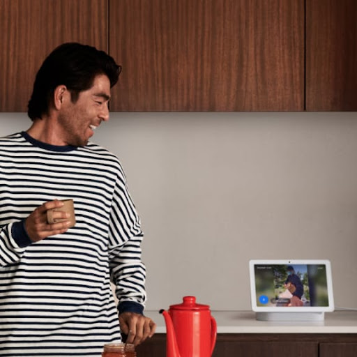 A man looks at Nest Hub in the kitchen.