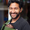 Smiling man carrying a tiny baby on him in a baby carrier.