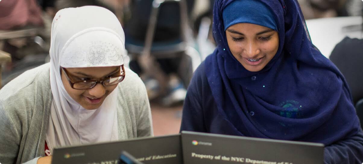 Dos alumnas con velo musulmán que trabajan con Chromebooks