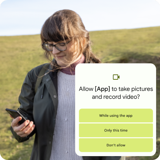 一个人站在长满草的山坡上看着 Android 手机。叠加的图像是一条信息，询问是否授权应用拍照和录制视频。权限选项包括“仅在使用该应用时允许”“仅限这一次”和“不允许”。
