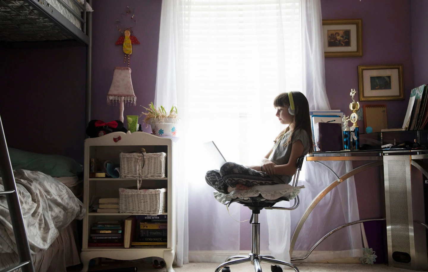 A girl sitting on a chair in her home, attending her virtual class through her laptop
