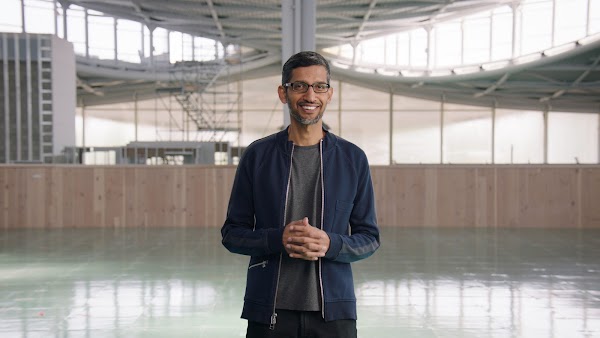 Sundar Pichai, Google and Alphabet’s CEO, standing inside of a building, smiling at the camera.