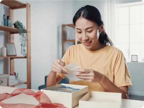 Una mujer abriendo un regalo y leyendo la tarjeta.