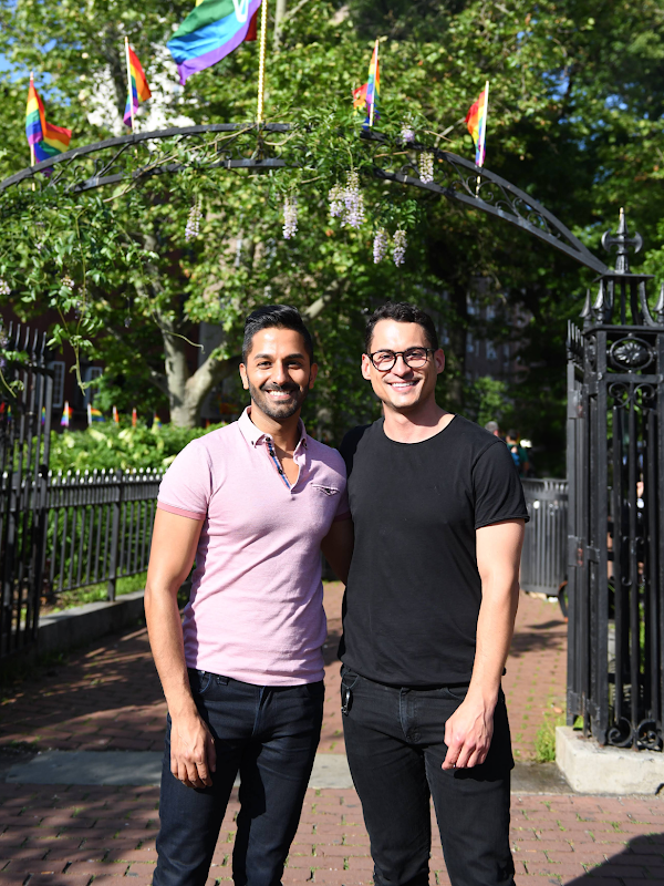Googlers Mohit Jolly (he/him) and Adam Wright (he/him) stand together and smile in front of Stonewall Park